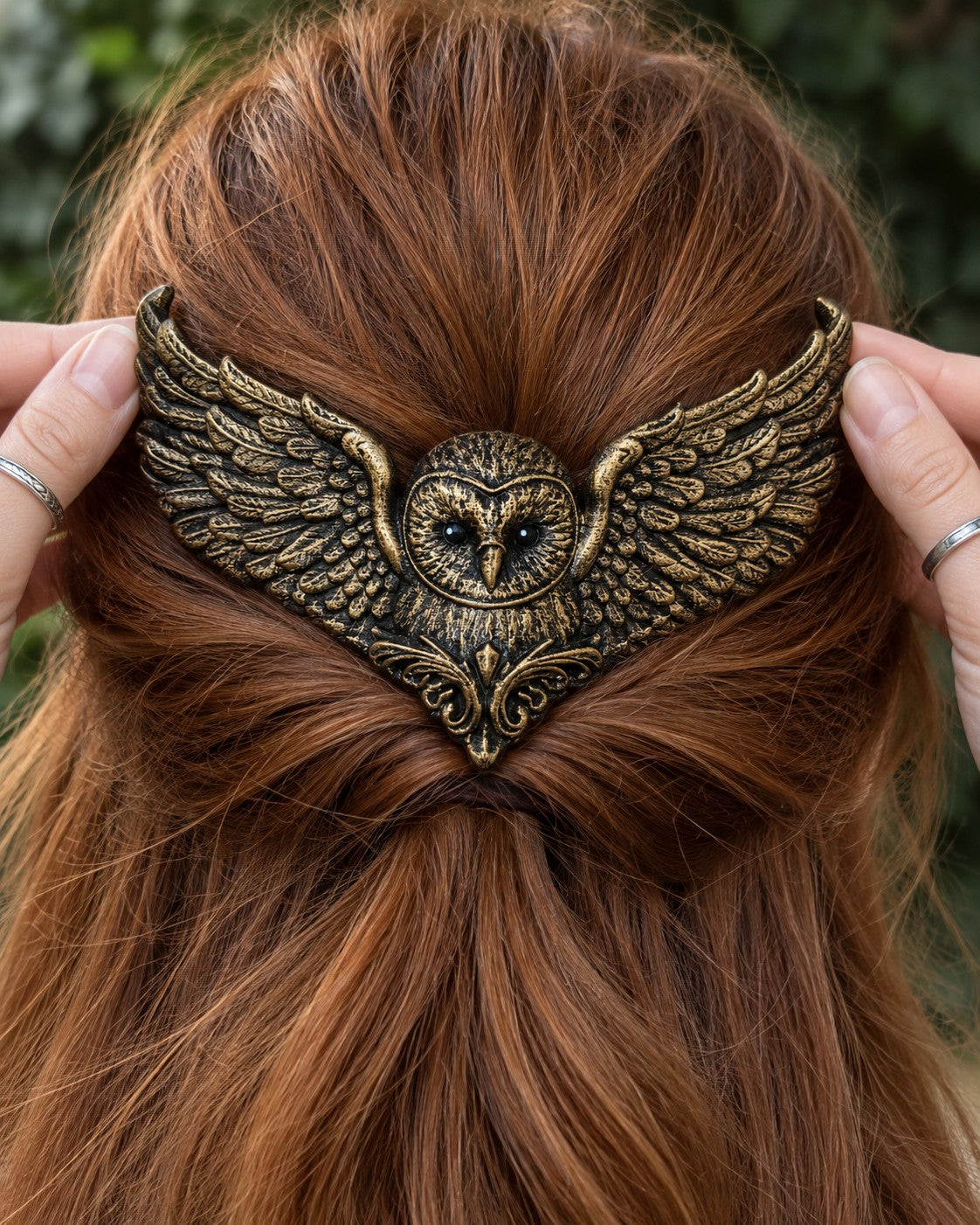 Two hands placing the Golden owl crown on a half-up twist of copper-red hair